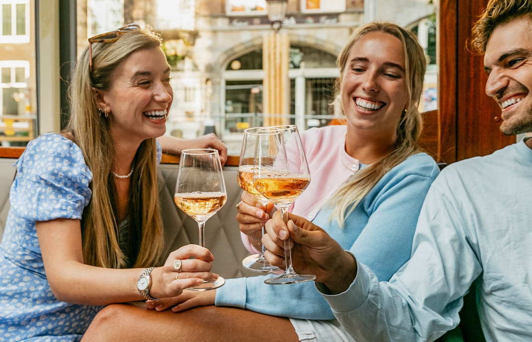 Three people cheering with their glasses of wint at a cafe in Port Aventura