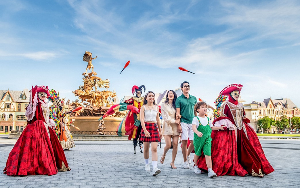Family enjoying entertainment activities at VinWonders with performers in colorful costumes.