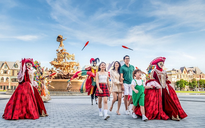 Family enjoying entertainment activities at VinWonders with performers in colorful costumes.