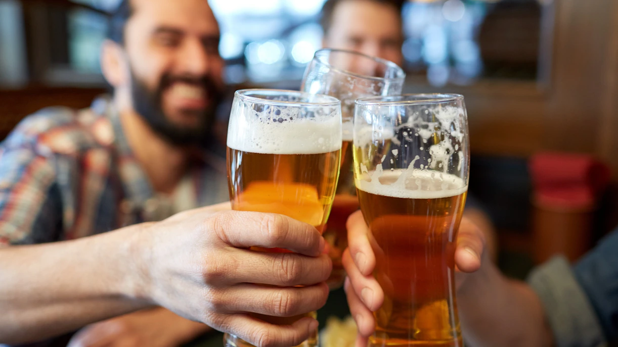 Cheers with beer glasses at a lively pub.