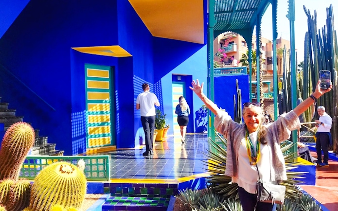 Jardin Majorelle visitor posing near vibrant blue building and cacti in Marrakech.