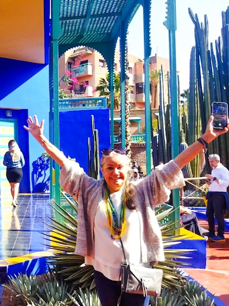 Jardin Majorelle visitor posing near vibrant blue building and cacti in Marrakech.