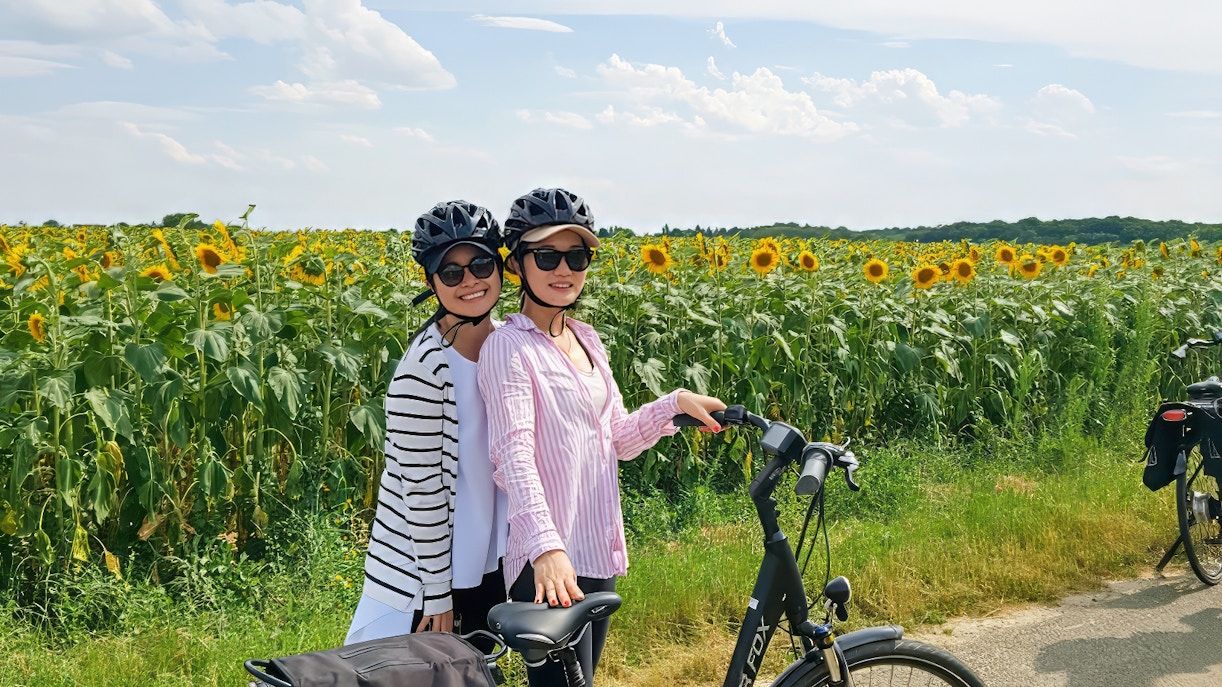 Women with the bike near sunflower fields