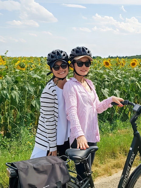 Two cyclists on an e-bike tour near a sunflower field in Chambord.