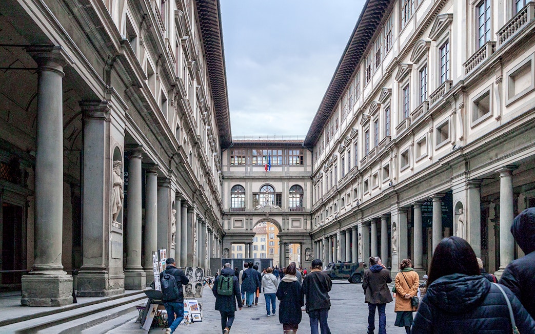 Uffizi Gallery courtyard in Florence with visitors walking through.