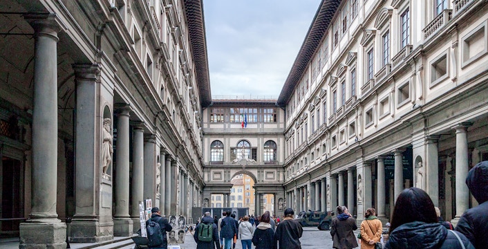 Uffizi Gallery courtyard in Florence with visitors walking through.
