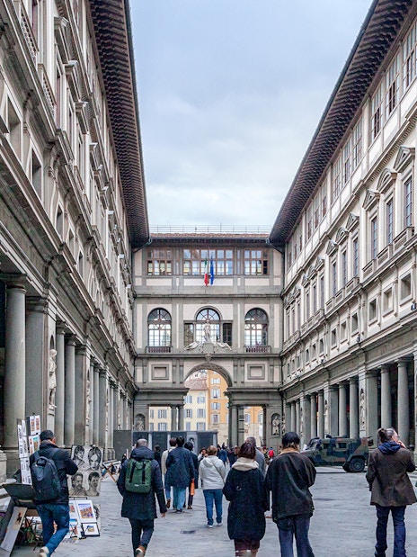 Uffizi Gallery courtyard in Florence with visitors walking through.