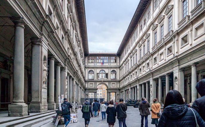 Uffizi Gallery courtyard in Florence with visitors walking through.