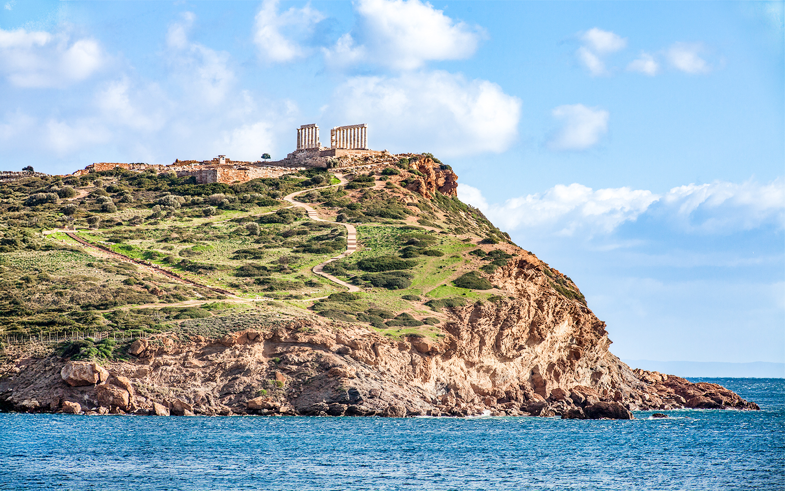 Temple of Poseidon on Cape Sounion cliff, Greece, overlooking the Aegean Sea.
