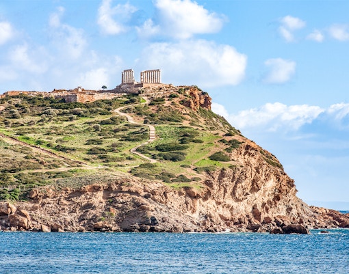 Temple of Poseidon on Cape Sounion cliff, Greece, overlooking the Aegean Sea.