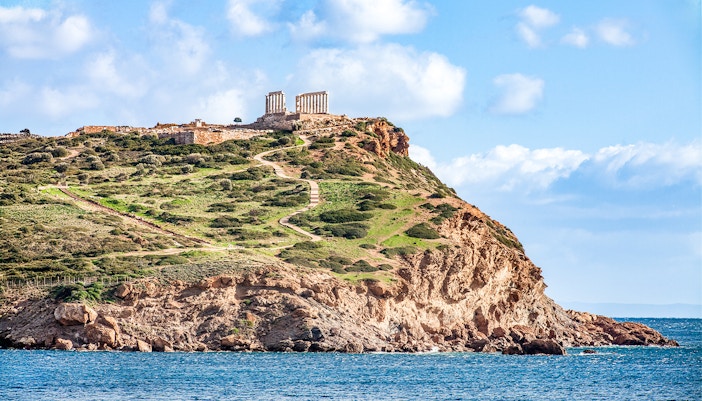 Temple of Poseidon on Cape Sounion cliff, Greece, overlooking the Aegean Sea.