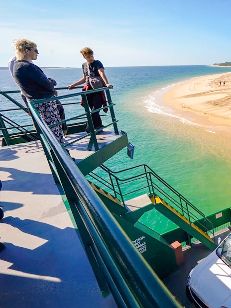 Ferry with vehicles approaching Fraser Island's sandy shore, K'gari.