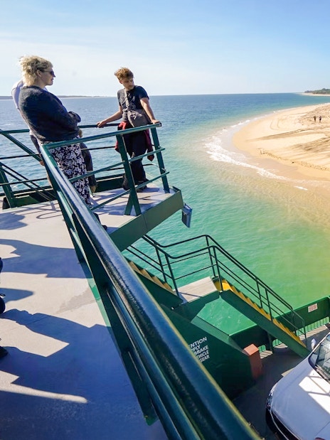 Ferry with vehicles approaching Fraser Island's sandy shore, K'gari.
