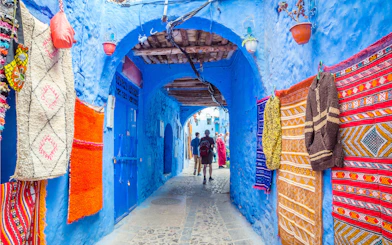 Street market with colorful textiles in blue medina of Chefchaouen, Morocco.