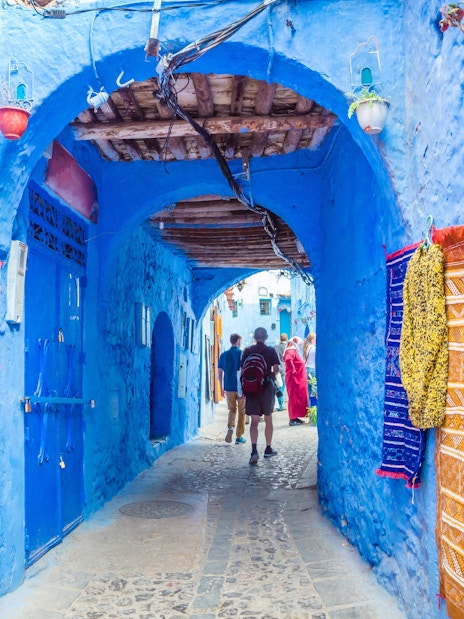 Street market with colorful textiles in blue medina of Chefchaouen, Morocco.