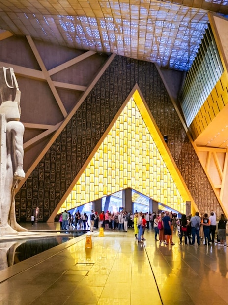 Grand Egyptian Museum atrium with statue and visitors, Cairo day trip from Hurghada.