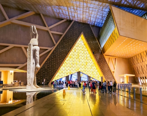 Grand Egyptian Museum atrium with statue and visitors, Cairo day trip from Hurghada.