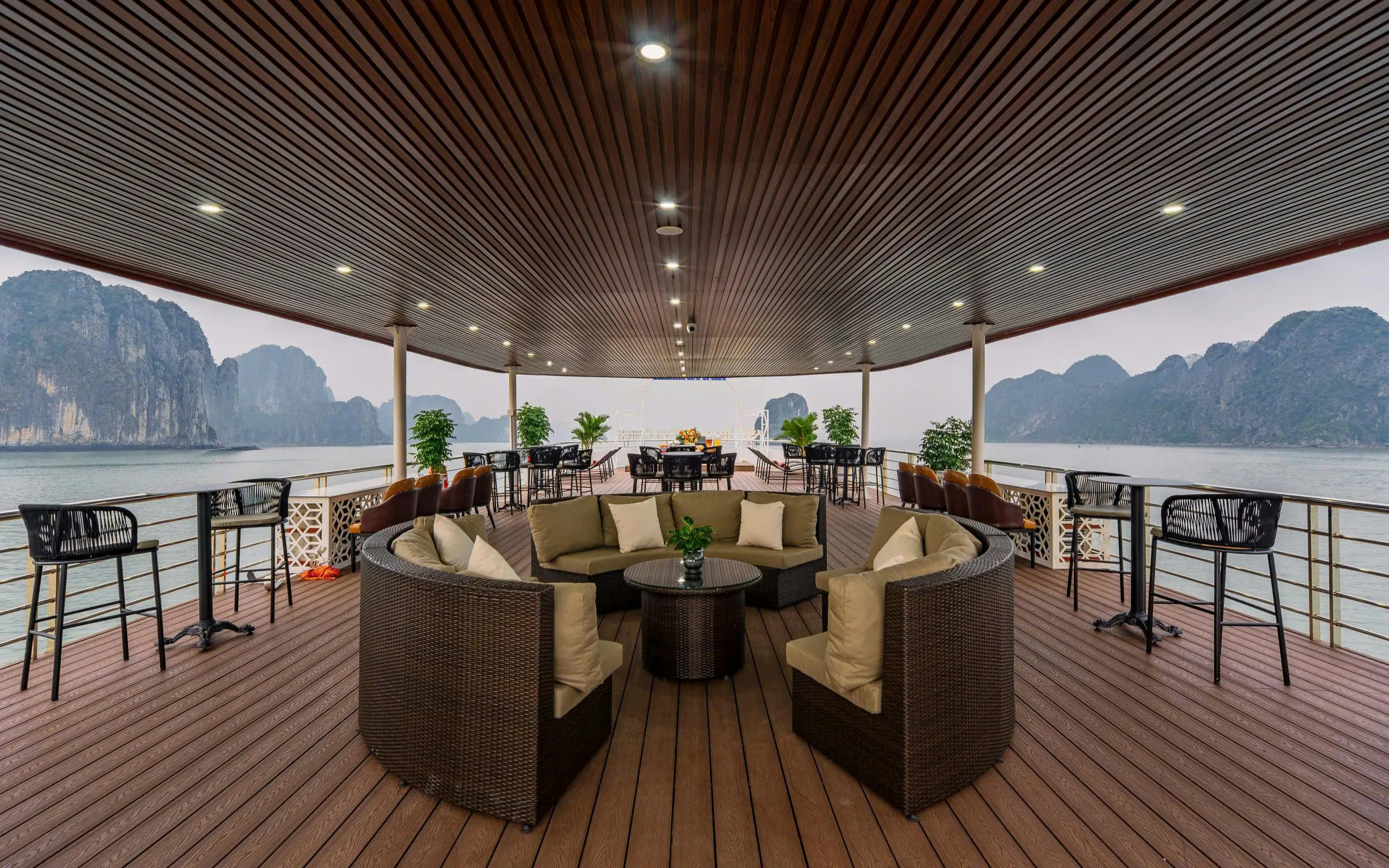 Luxury cruise deck with seating overlooking Ha Long Bay limestone karsts.