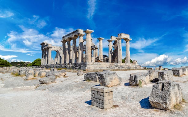 Aphaia Temple ruins with Doric columns on Aegina Island, Greece under a clear blue sky.