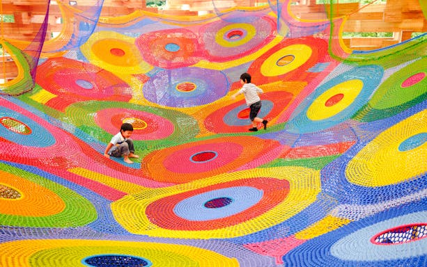Children playing on colorful net installation at Hakone Open-Air Museum.