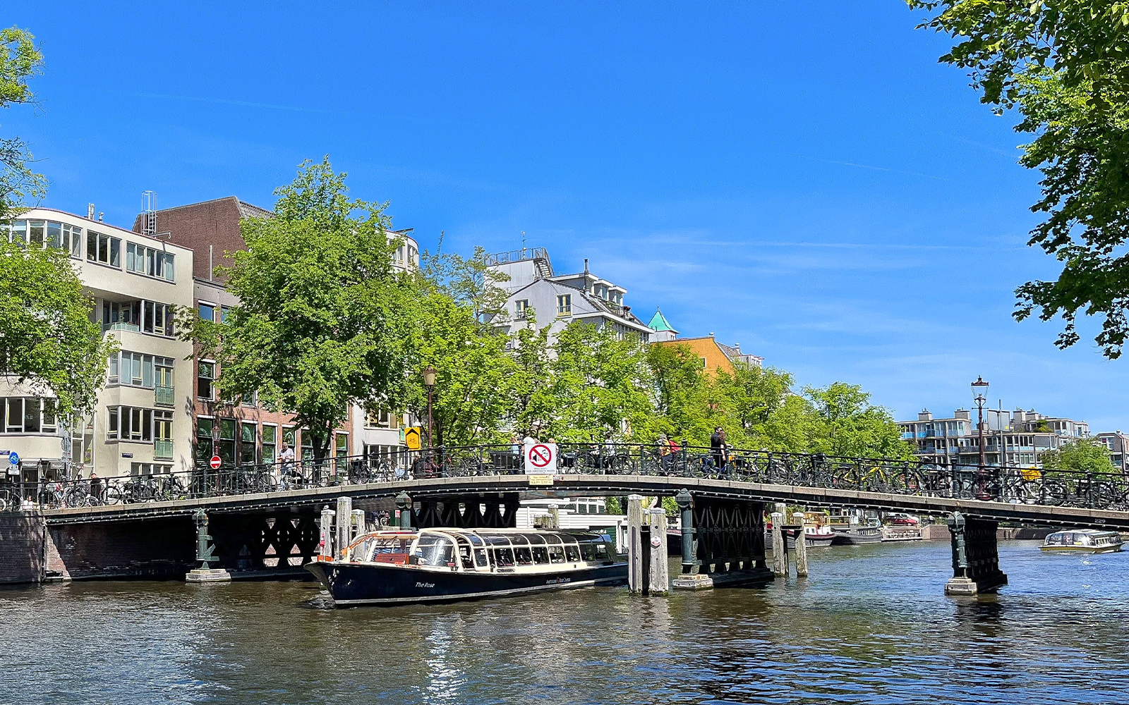 Canal boat passing under a bridge in Amsterdam.