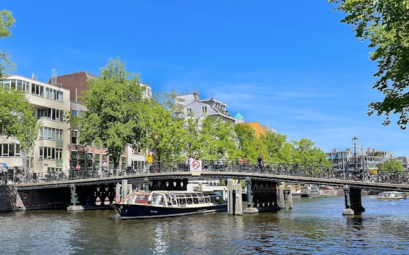 Canal boat passing under a bridge in Amsterdam.