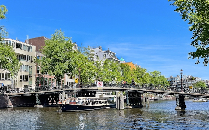 Canal boat passing under a bridge in Amsterdam.