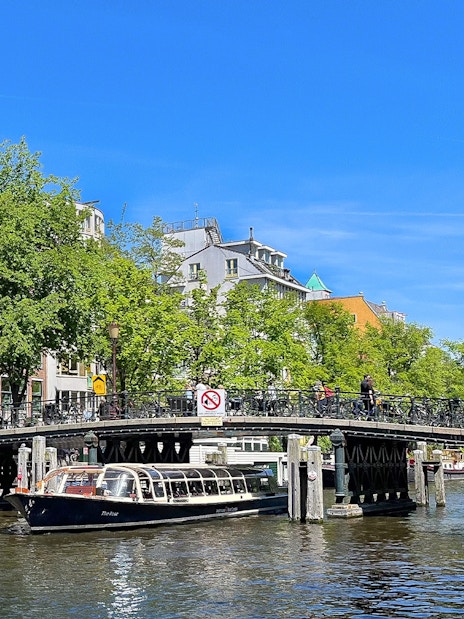 Canal boat passing under a bridge in Amsterdam.
