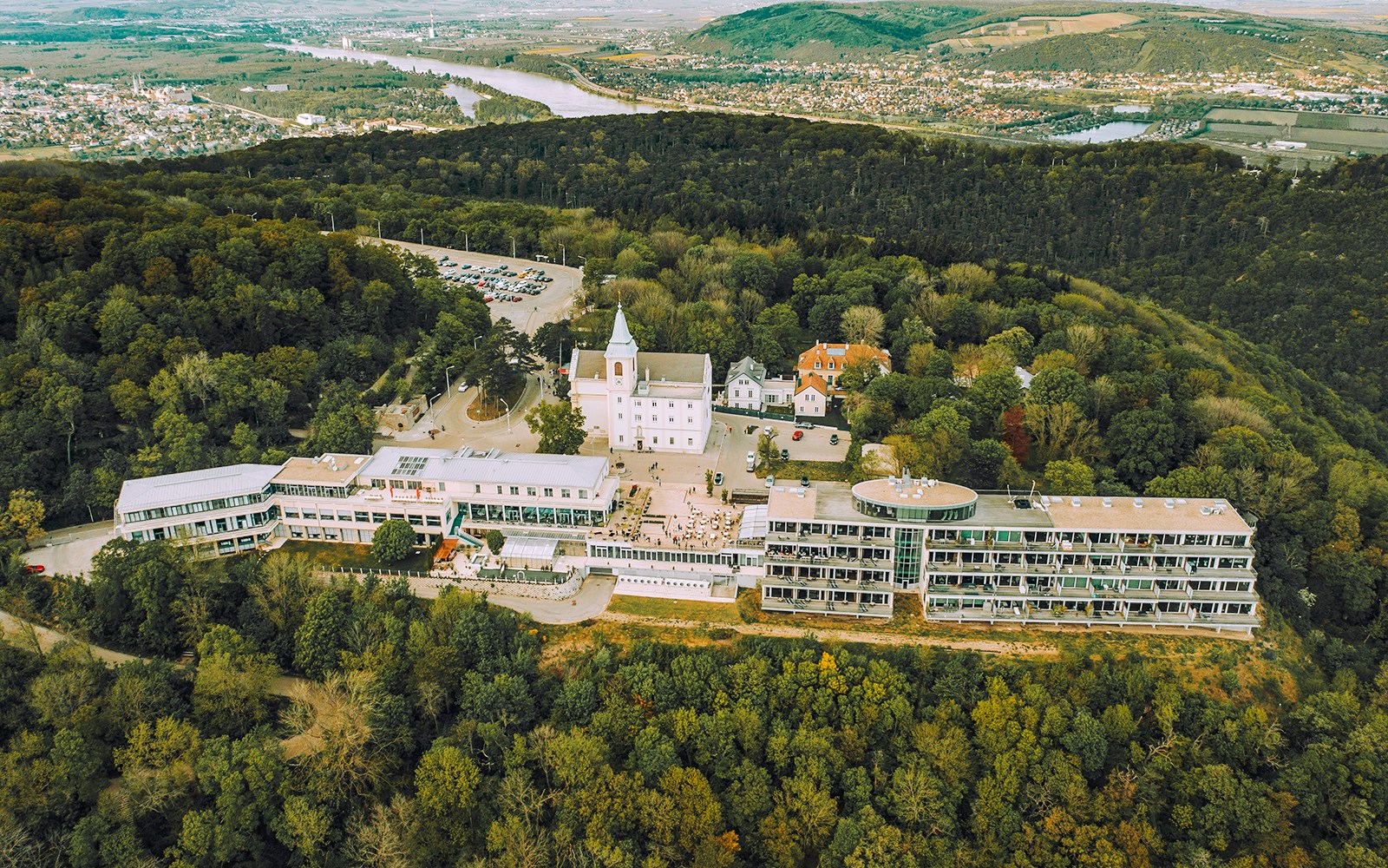 Aerial view of St. Joseph Church on Kahlenberg hill near Vienna, Austria, surrounded by forest.