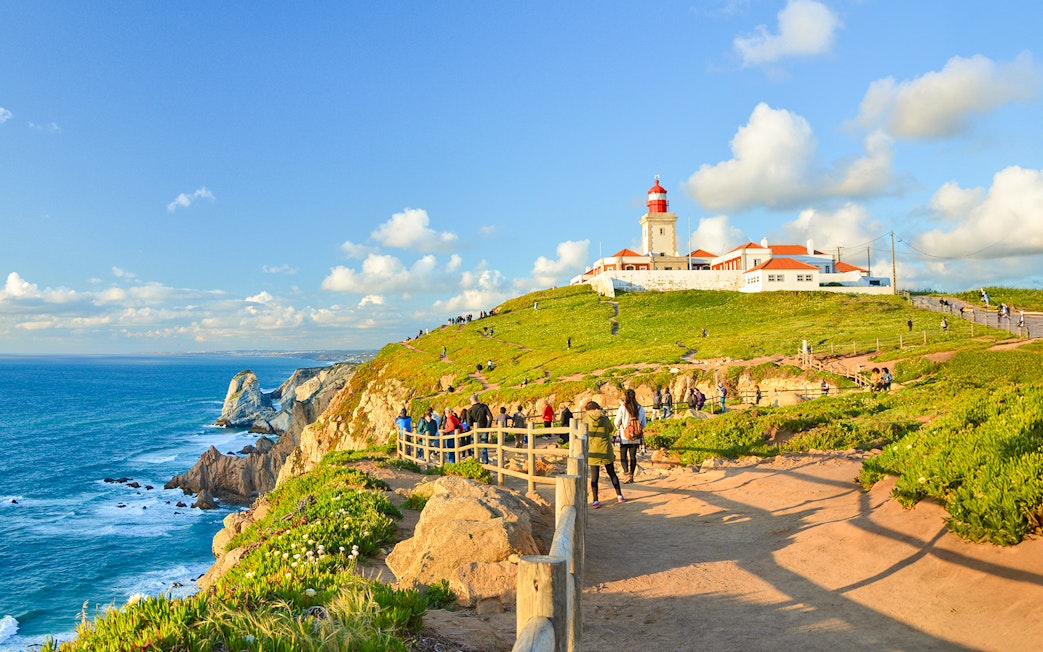 Tourists walking along the path near the lighthouse at Cabo da Roca, Portugal.