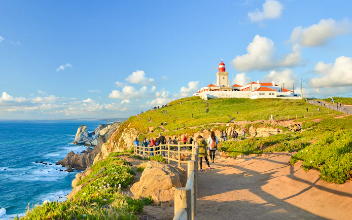 Tourists walking along the path near the lighthouse at Cabo da Roca, Portugal.