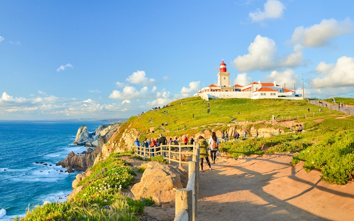 Tourists walking along the path near the lighthouse at Cabo da Roca, Portugal.