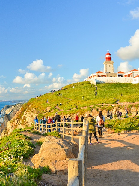 Tourists walking along the path near the lighthouse at Cabo da Roca, Portugal.