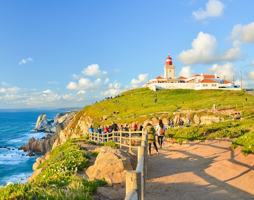 Tourists walking along the path near the lighthouse at Cabo da Roca, Portugal.