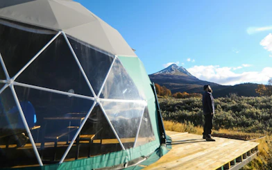 Geodesic dome and person with mountain view in Tierra del Fuego National Park.