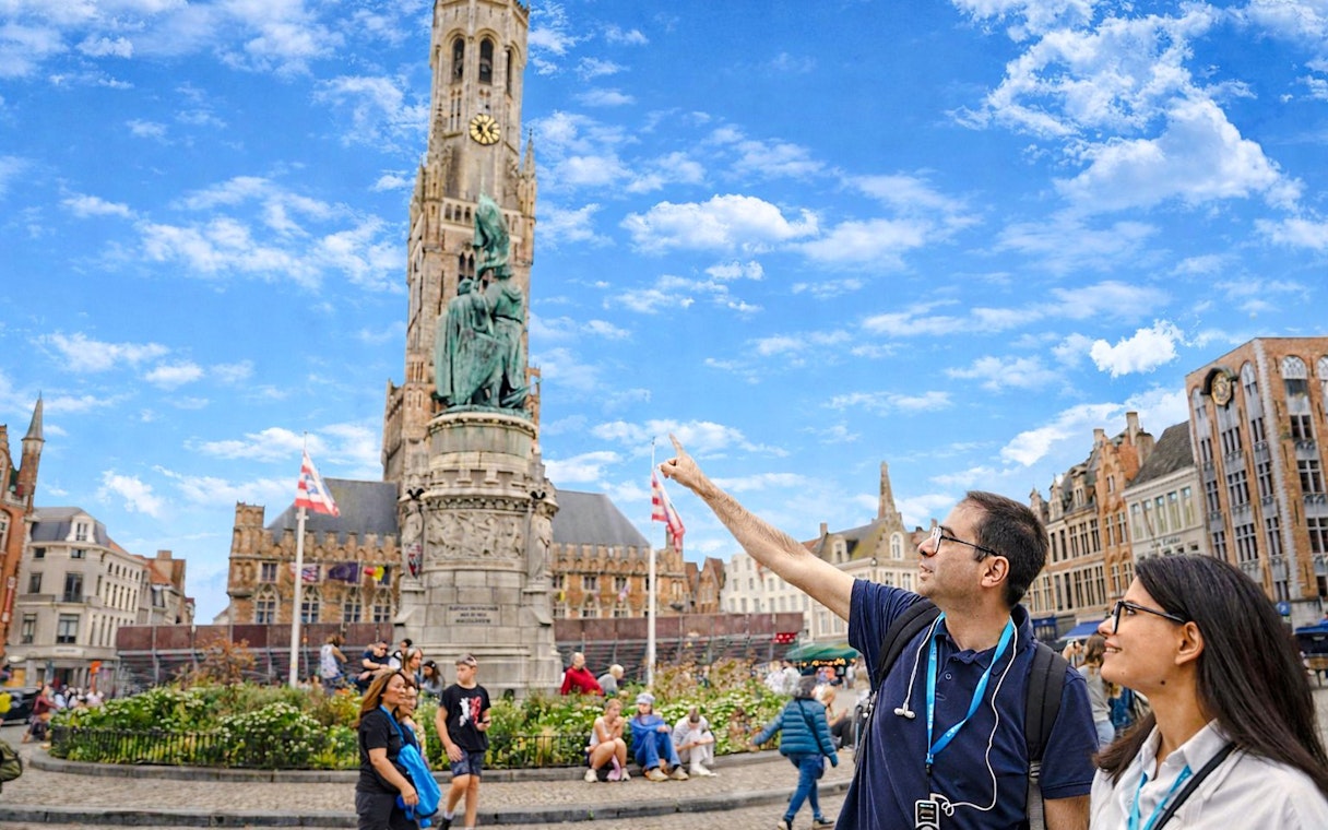 Visitors at Market Square in Bruges, Belgium, with the Belfry of Bruges in the background.