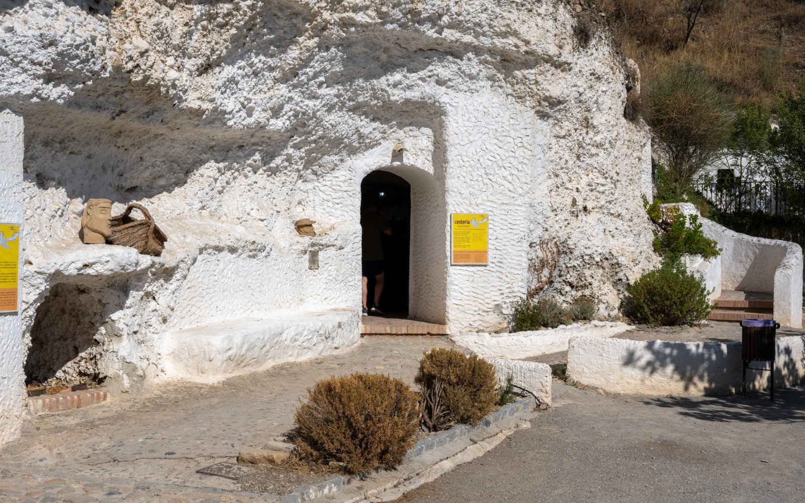 Entrance to Cuevas del Sacromonte Museum in Granada, Spain, with white cave walls and informational signs.