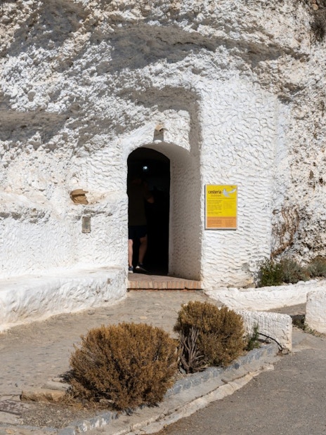 Entrance to Cuevas del Sacromonte Museum in Granada, Spain, with white cave walls and informational signs.