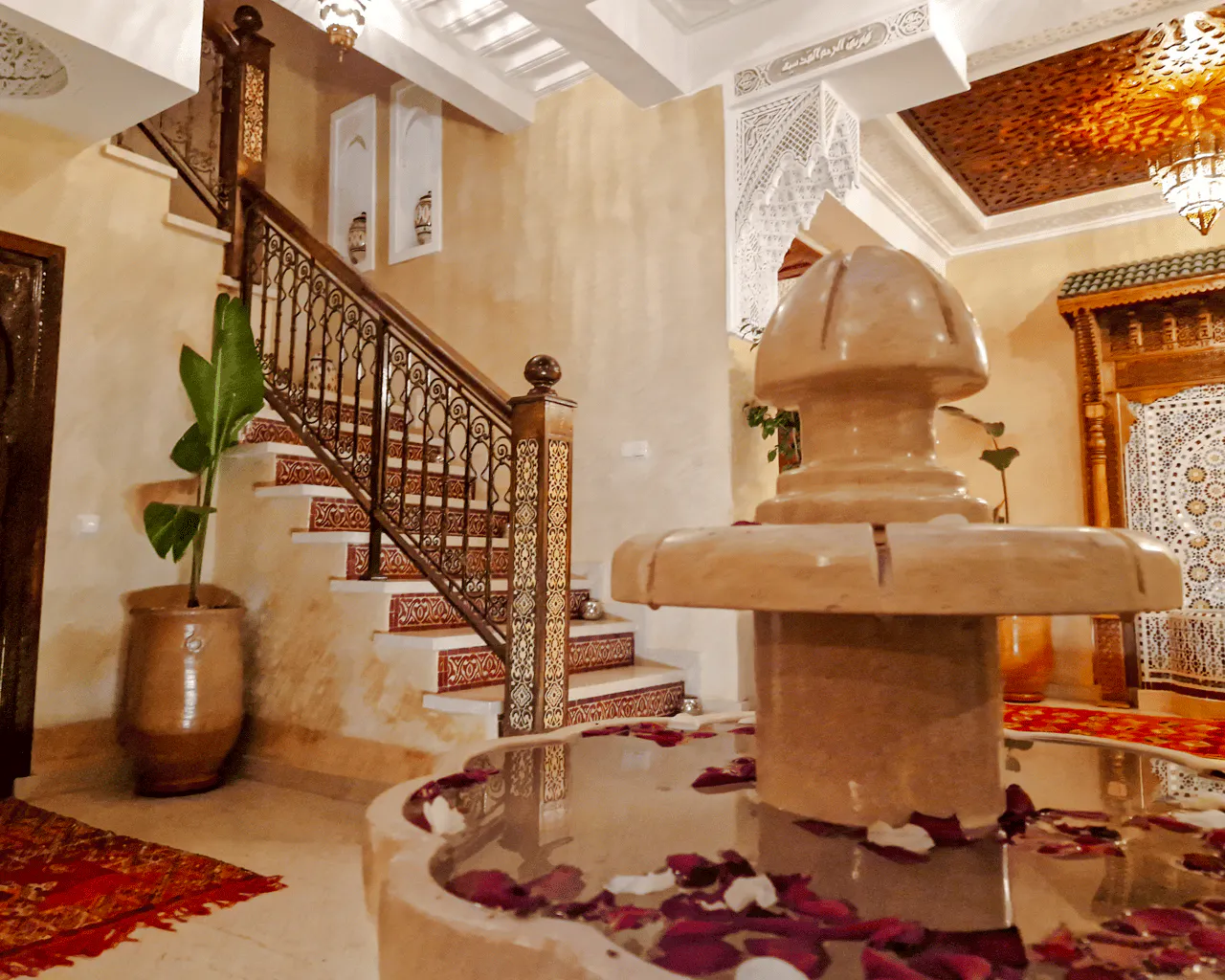 Moroccan interior with ornate staircase and fountain, Marrakech Hammam experience.