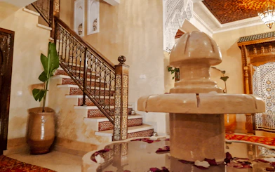 Moroccan interior with ornate staircase and fountain, Marrakech Hammam experience.