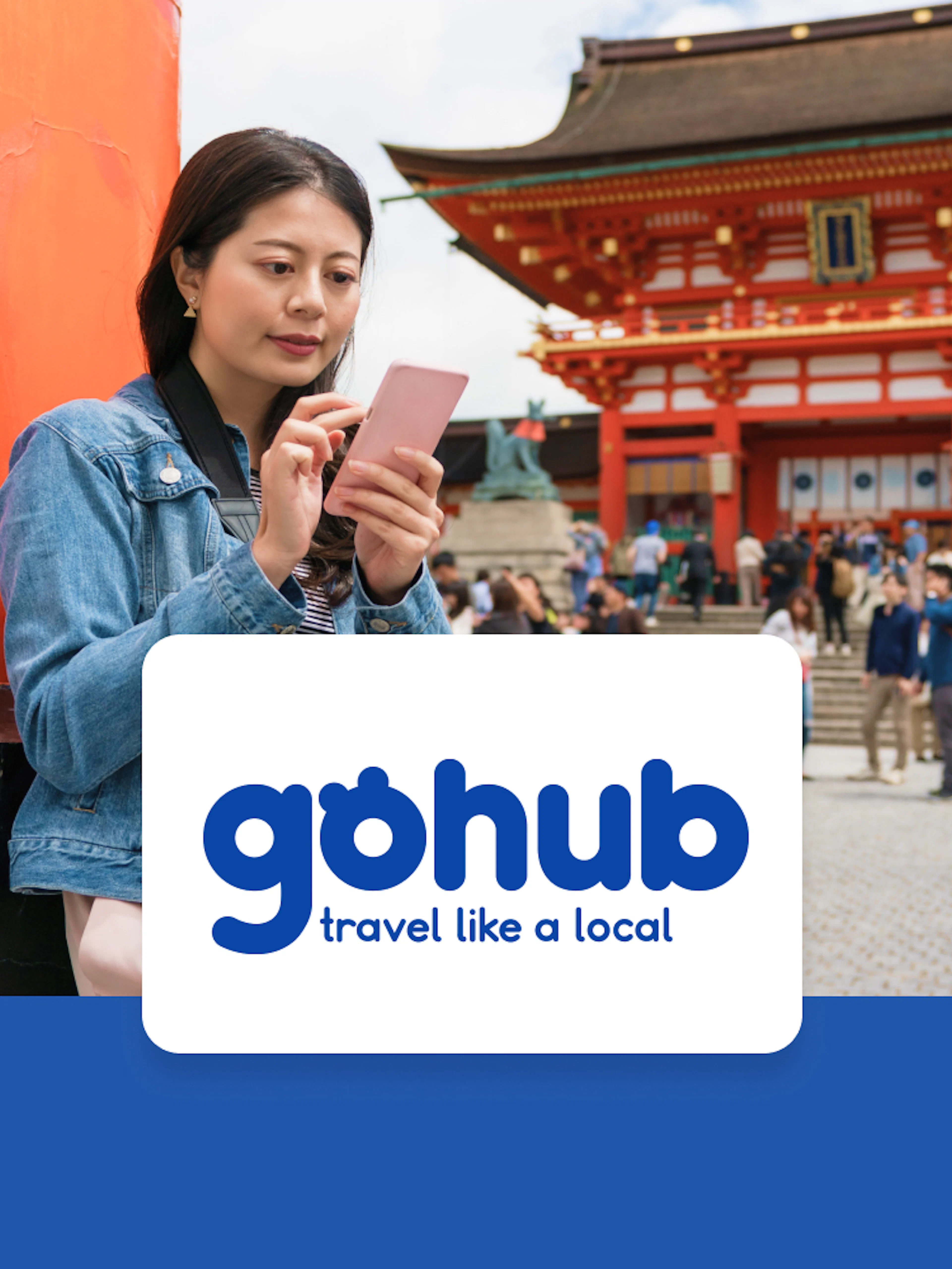 Asian traveler reading guide on phone near Fushimi Inari Taisha Shrine, Kyoto.
