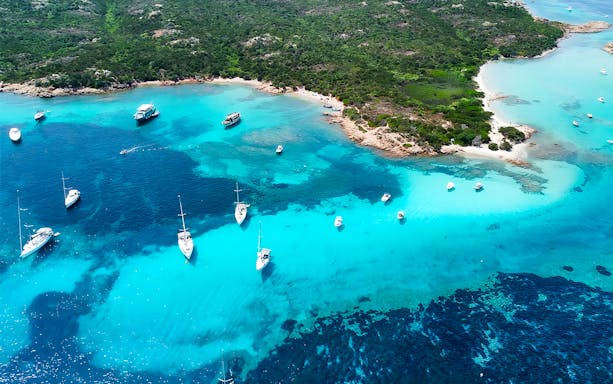Motorboats anchored in turquoise waters of La Maddalena Archipelago, Italy.