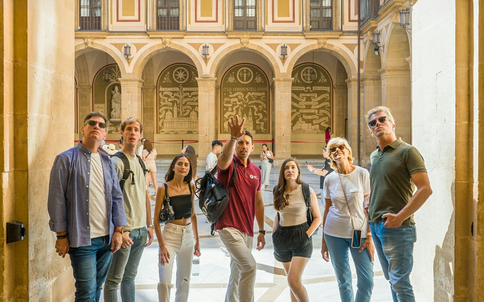 Group on a guided tour inside Montserrat Monastery, observing architectural details.