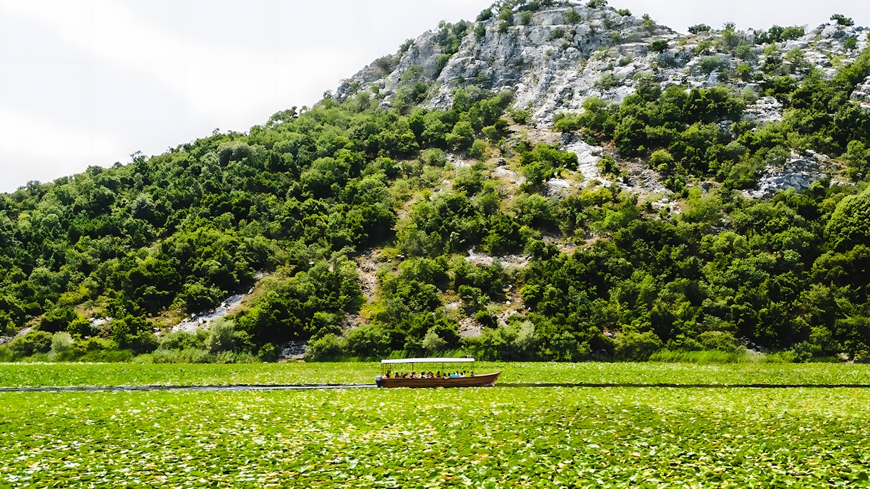 Wooden boat on Lake Skadar with lush green hills in the background.