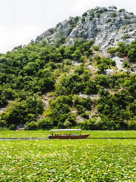 Wooden boat on Lake Skadar with lush green hills in the background.