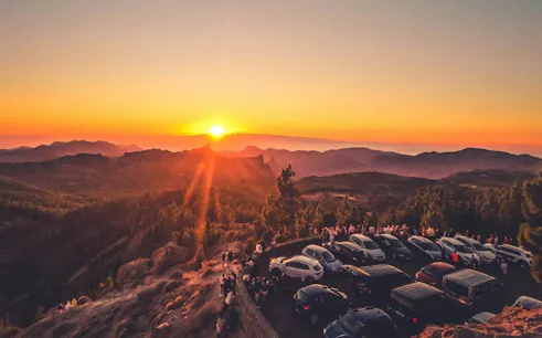 Gran Canaria sunset view with parked cars and tourists on a volcano tour.