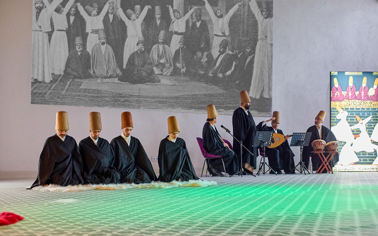 Whirling Dervishes performing in traditional attire with musicians in Turkey.