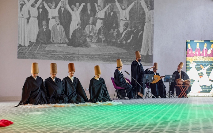 Whirling Dervishes performing in traditional attire with musicians in Turkey.