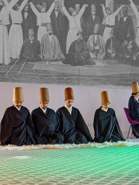 Whirling Dervishes performing in traditional attire with musicians in Turkey.