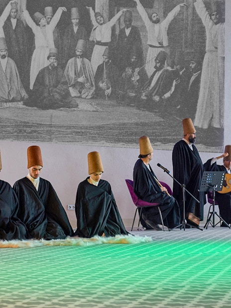 Whirling Dervishes performing in traditional attire with musicians in Turkey.